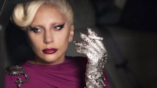 Lady Gaga holds a cigarette in a fancy glove in American Horror Story: Hotel.