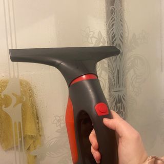 Image of window vacuum being used to clean glass divider in bathroom