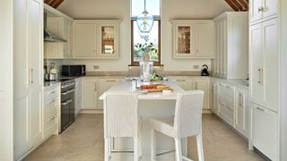 white Shaker kitchen with narrow kitchen island with white wicker bar stools