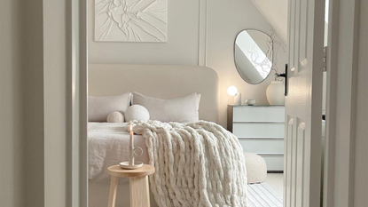 A neutral vanilla girl aesthetic bedroom with cozy throw blanket and pebble mirror