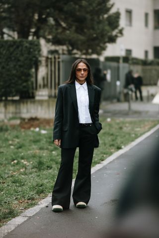 a guest at Milan Fashion Week wearing a corporate slouchy black suit