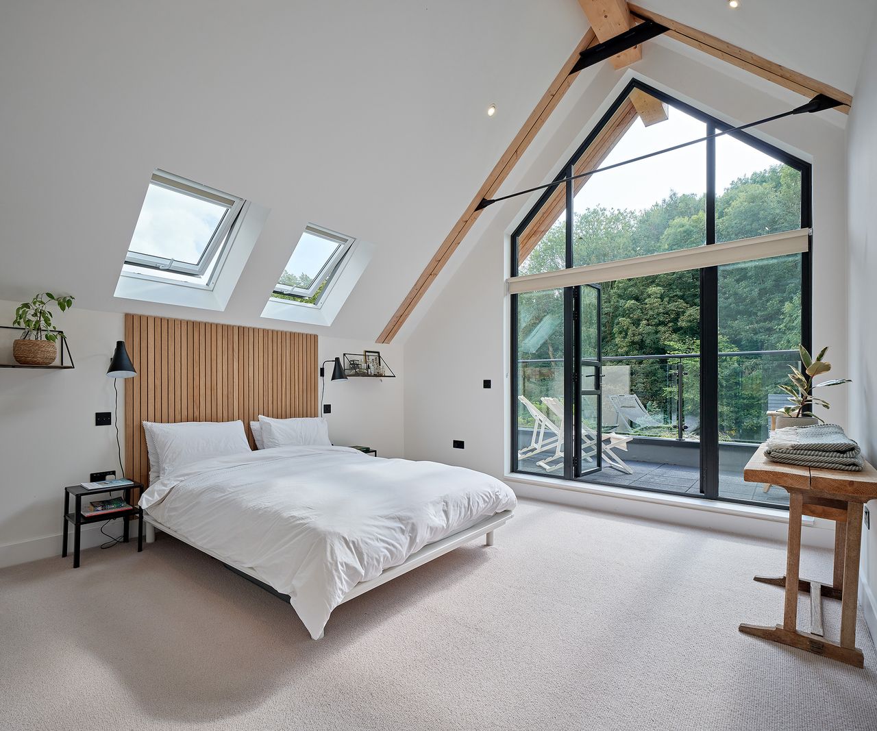 A view of a loft bedroom in a self build home with large glass doors opening onto a balcony