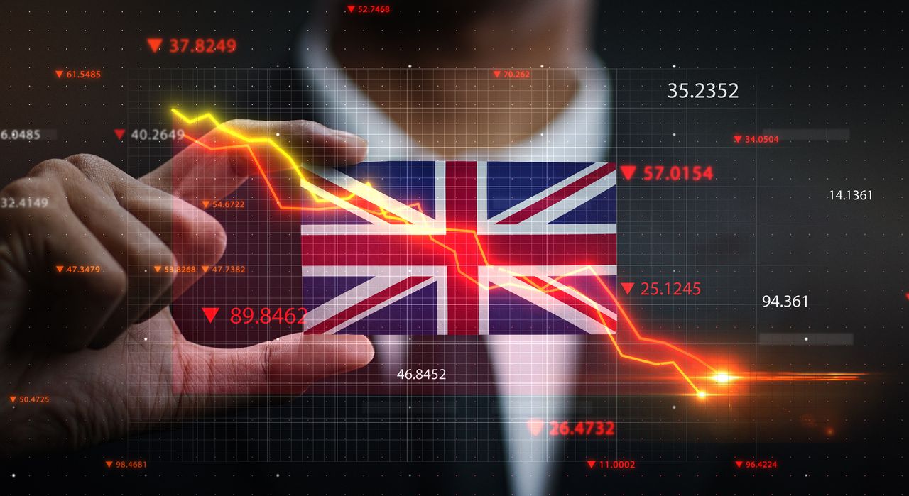 Concept art of a downward-trending share price chart in front of UK flag held by a businessman