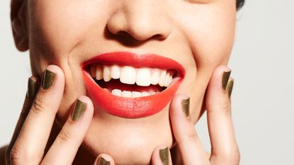 woman with red lipstick and gold nail polish on