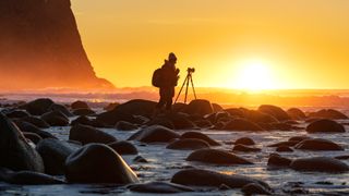 Woman photographing sunset at Unstad beach, Norway