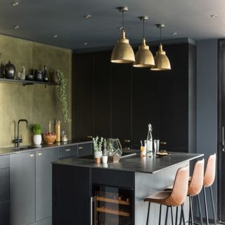 black kitchen island with leather brown stools, black cabinets and gold pendant lights
