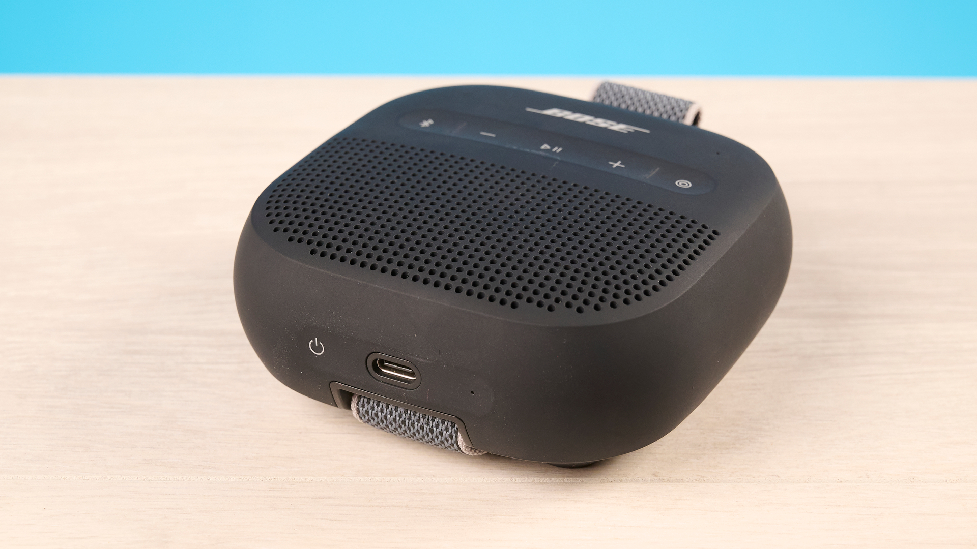 Bose SoundLink Micro 2 in black photographed in front of a blue background