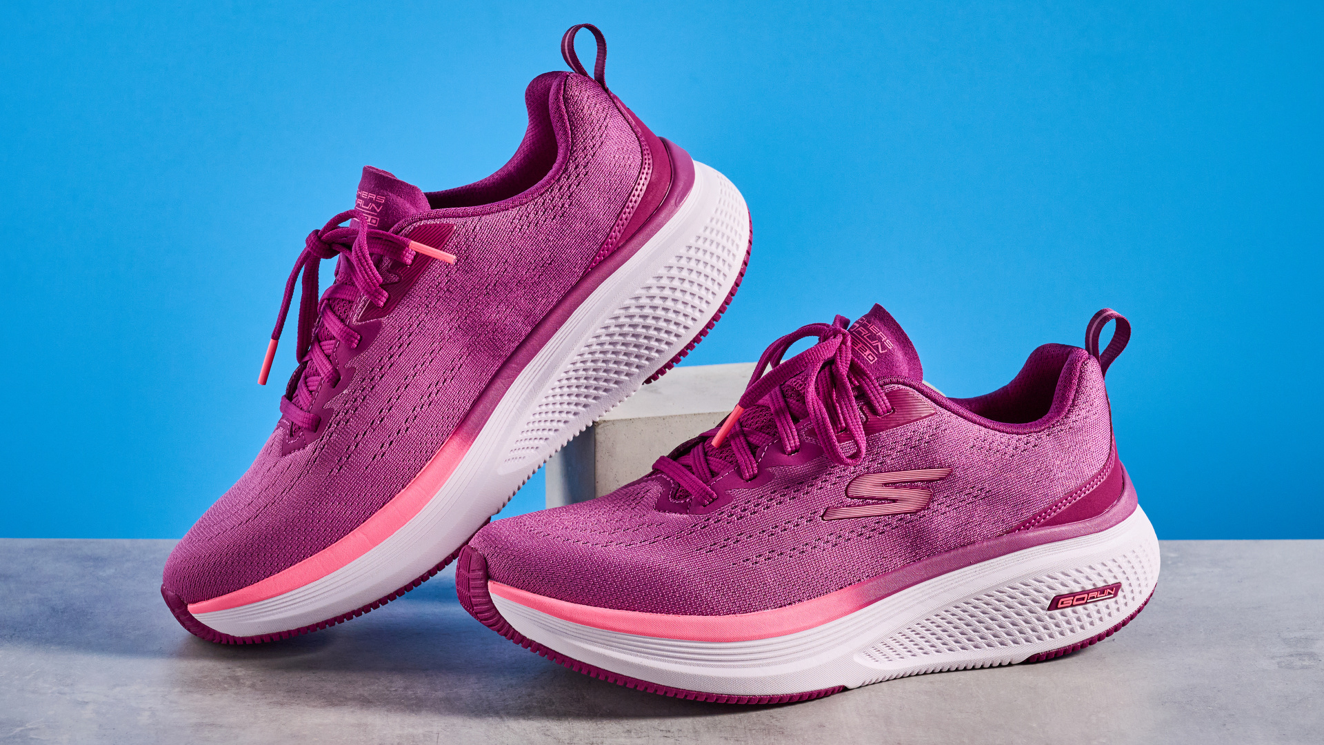 the skechers go run elevate 2.0 running shoes in the women&#039;s style, in fuchsia pink, photographed against a blue background