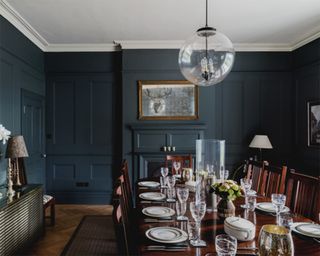 Navy dining room with glass sphere pendant light and mahogany dining set