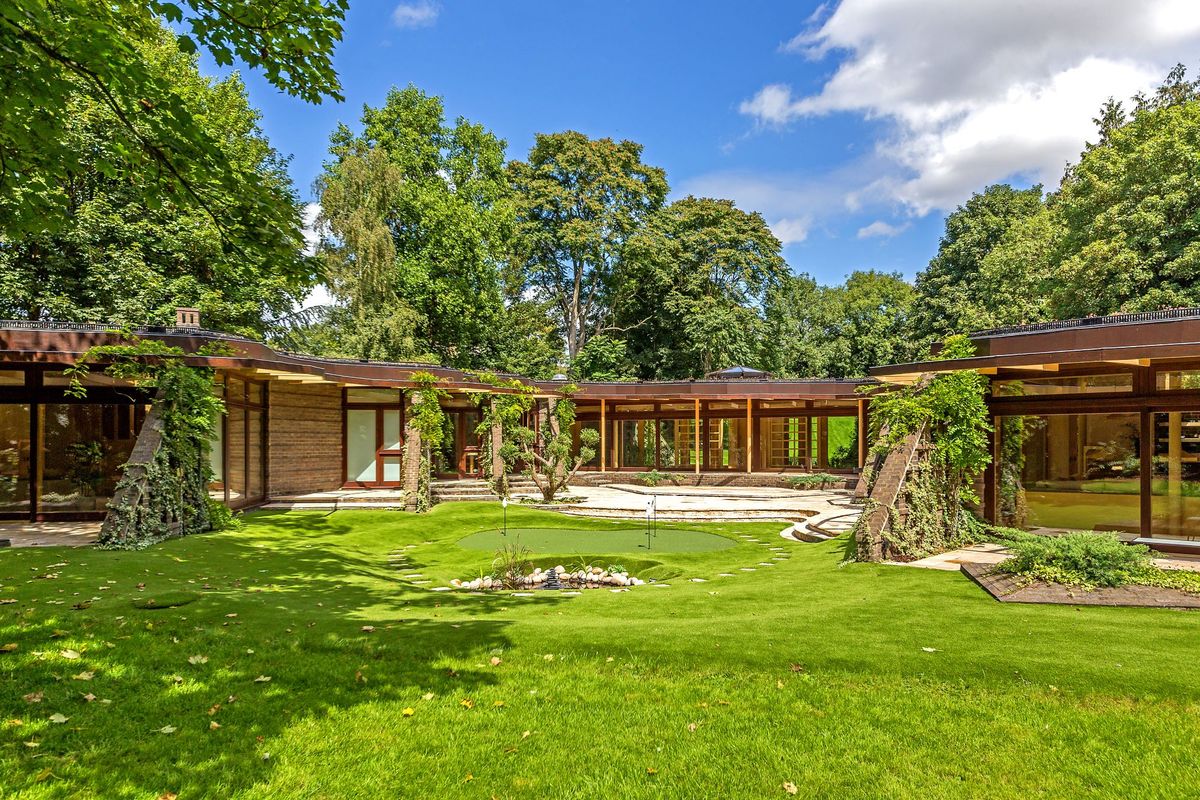 A view from outside the zig zag home with the lawn at the forefront of the image