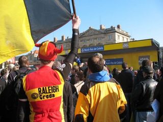 A fan in vintage outfit cheers on his favorite riders with a Belgian flag at the start in Compiegne