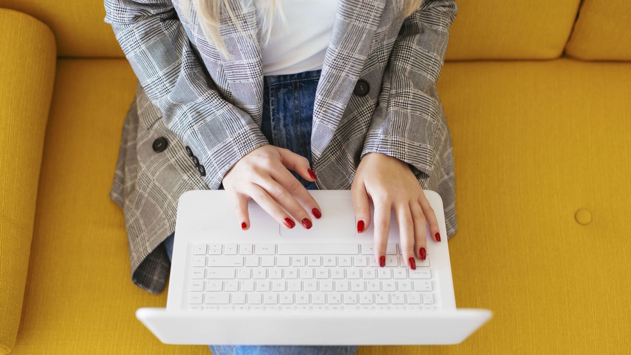 Businesswoman sitting on yellow couch, using laptop