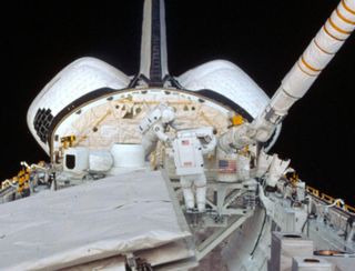 Kathy Sullivan and Dave Leestma work on the orbital refueling experiment during a spacewalk.