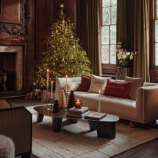 A living room with a cream sofa and a modern coffee table decorated for Christmas