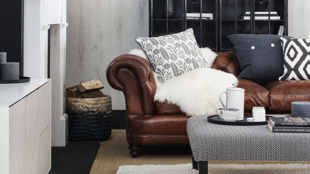 Neutral living room with brown leather chesterfield sofa dressed with white sheepskin throw and monochrome cushions