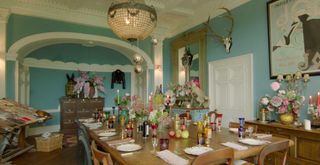 turquoise dining room with table filled with colourful candles and dinnerware in Alice Temperley's house