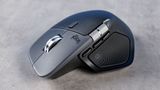 A sleek, ergonomic wireless mouse on a gray surface. It features a metallic scroll wheel and textured side grips, conveying a modern, professional design.