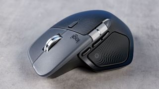 A sleek, ergonomic wireless mouse on a gray surface. It features a metallic scroll wheel and textured side grips, conveying a modern, professional design.
