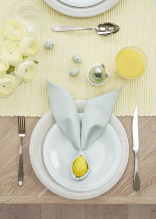 pale blue napkins used to make easter inspired place settings on yellow tablecloth by john lewis & partners