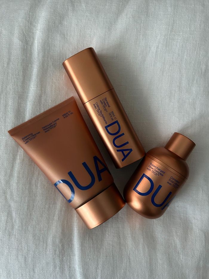 The Dua Lipa x Augustinus Bader skincare range on a white linen background