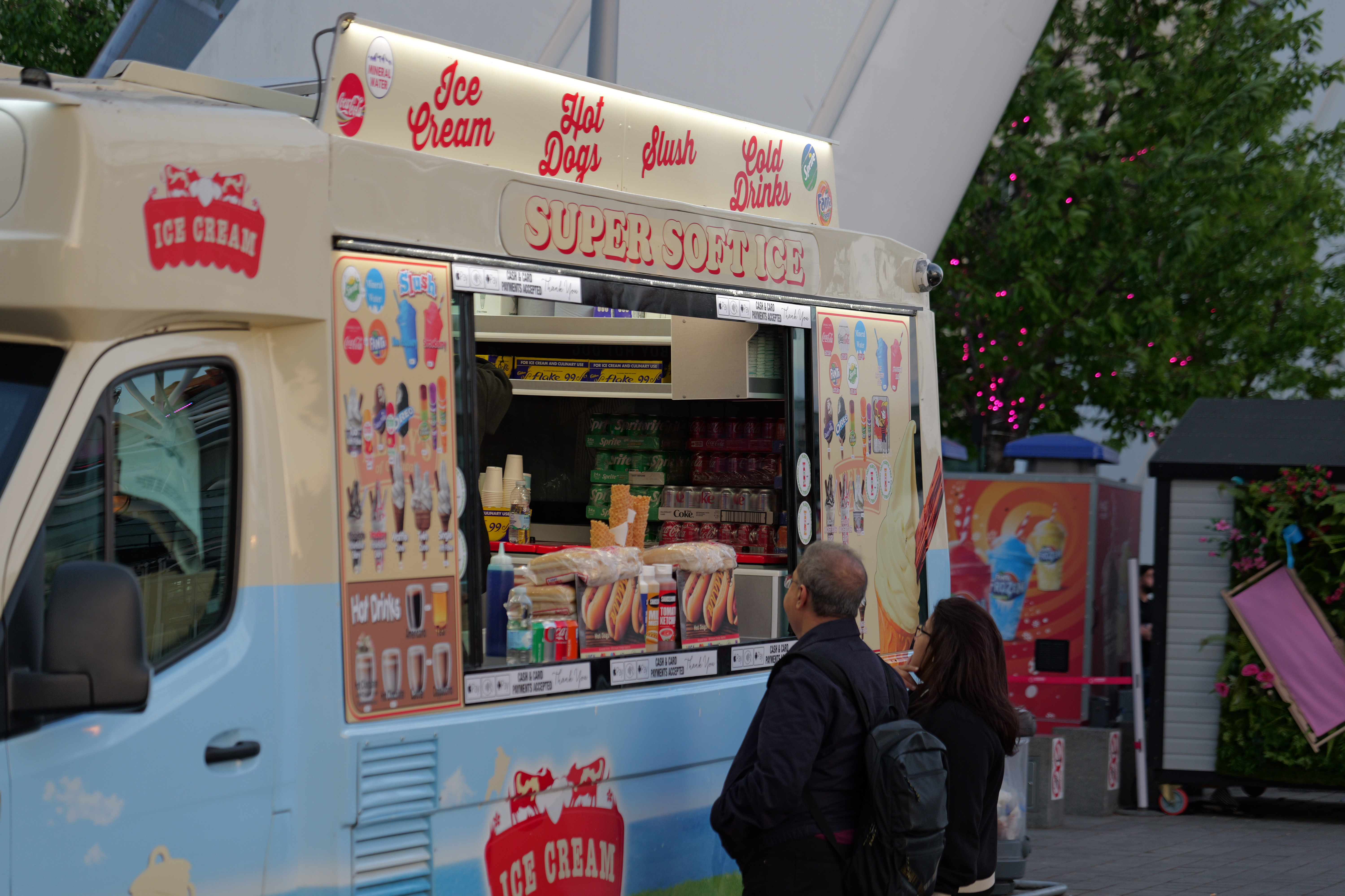 A ice cream van with two people waiting to buy ice cream
