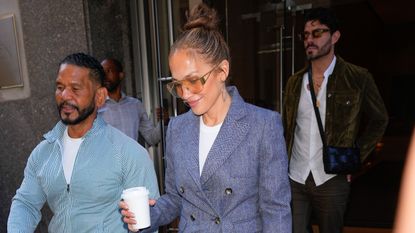 Jennifer Lopez wearing a tailored blue blazer with wide-leg Gucci jeans, white sneakers, and a white Hermès Birkin bag in New York City July 2024