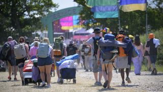 Isle of Wight festival entrance with people carrying their camping gear.