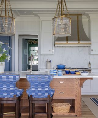 Blue and white marble kitchen with large kitchen island, blue bar stools, gold and glass pendant lights, marble backsplash, blue cabinet, tongue & groove wall paneling above door and across ceiling