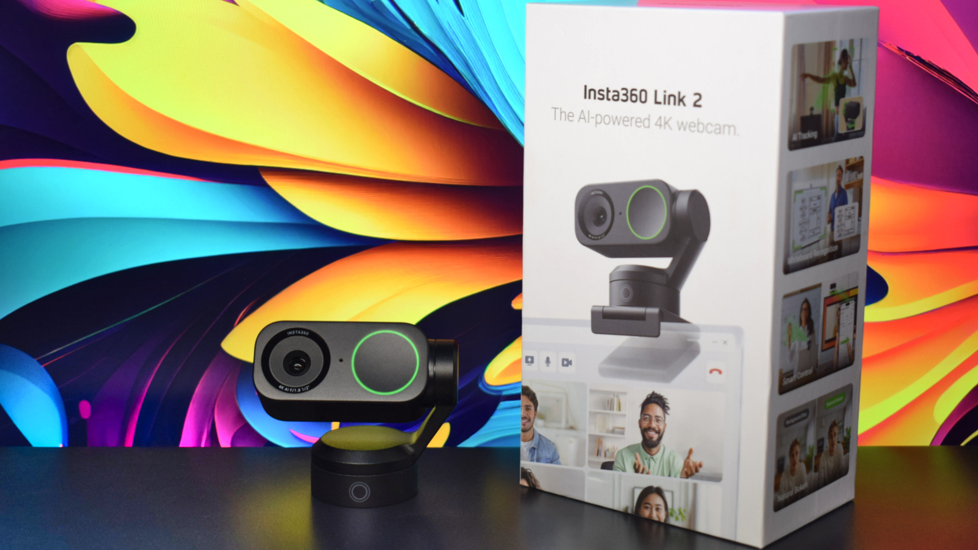 Photo of the Insta360 Link 2 4k webcam showing the camera next to its packaging and in front of a colorful backdrop.