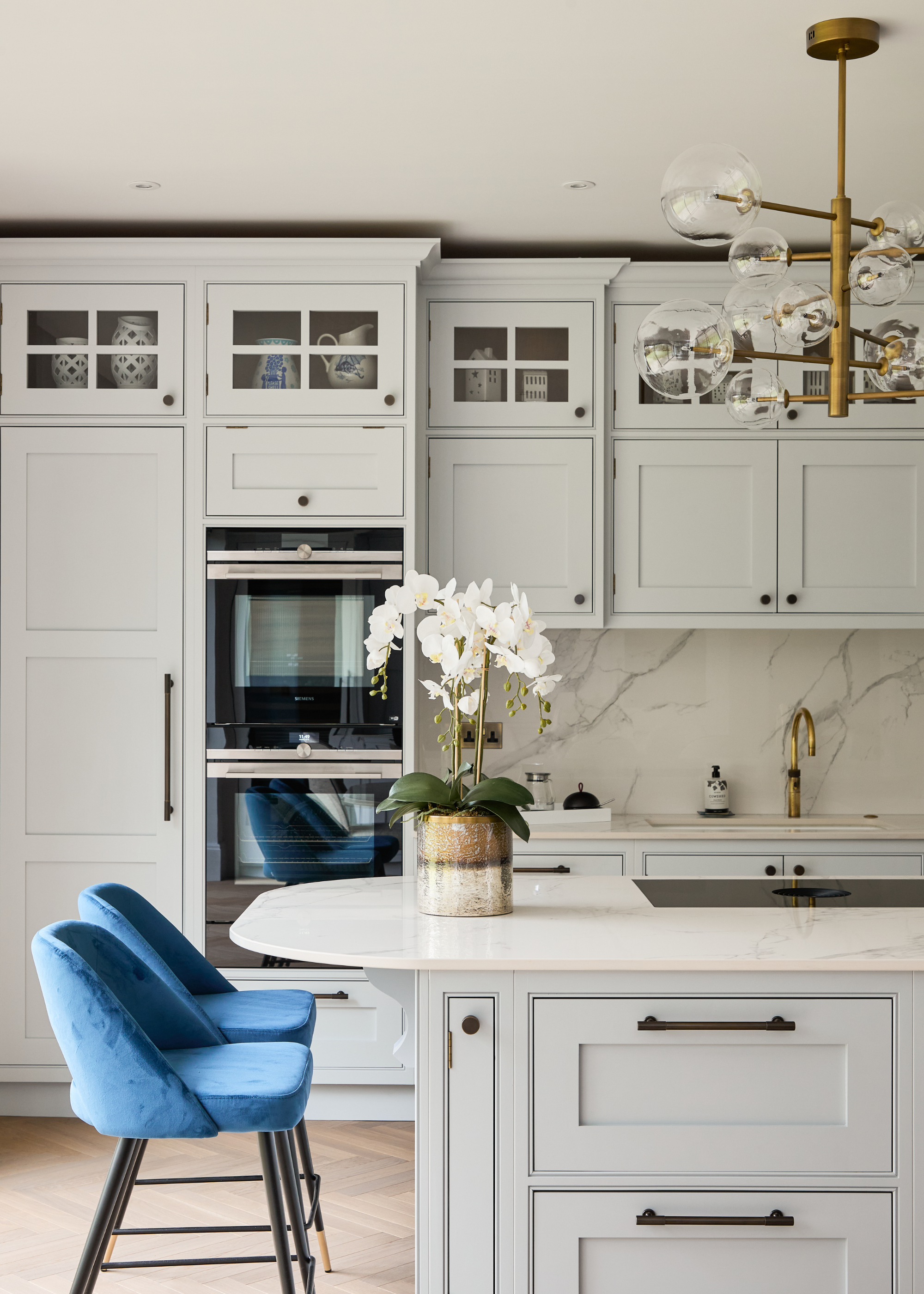 A pale blue/gray kitchen with a modern twist of electric blue bar chairs and sleek surfaces