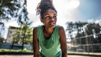 A young woman puts her hands on her knees in the middle of a sweaty workout