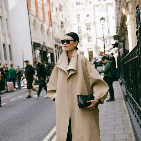 woman wears voluminous trench coat in the street. 