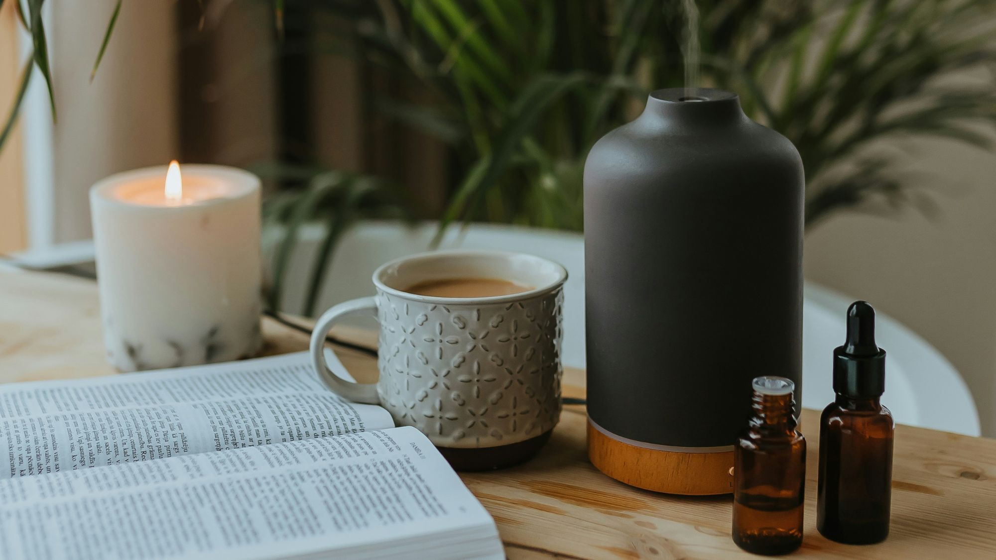 candle, tea, diffuser, book and supplements on a wooden table
