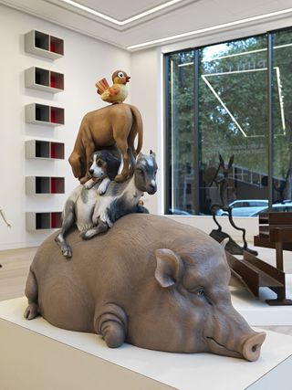 A sculpture of animals lying on top of each other. We have a pig, a goat, two dogs, and a bird.