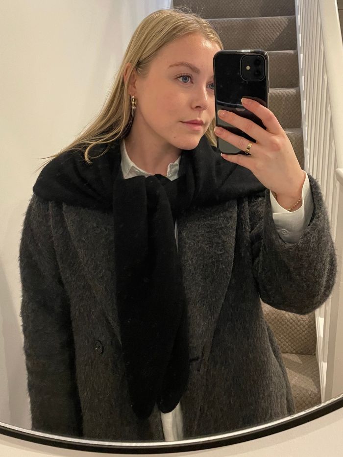 Florrie wears a cashmere scarf, grey coat and white shirt