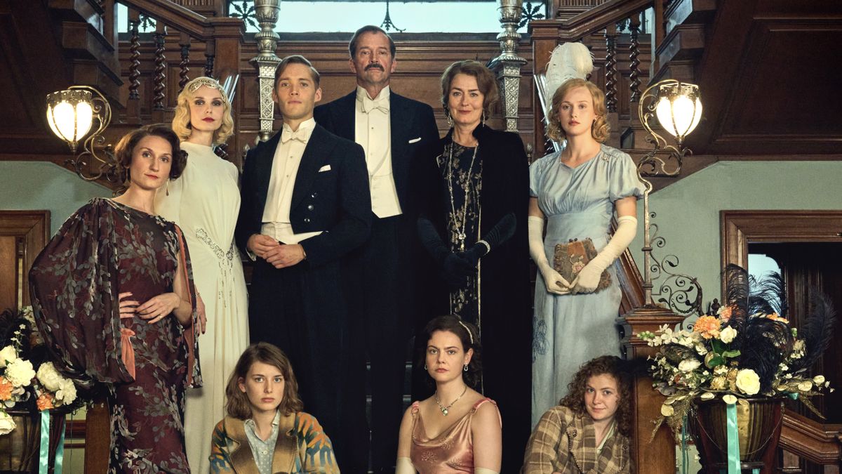 The cast of Outrageous in 1930s costume stand together on a staircase