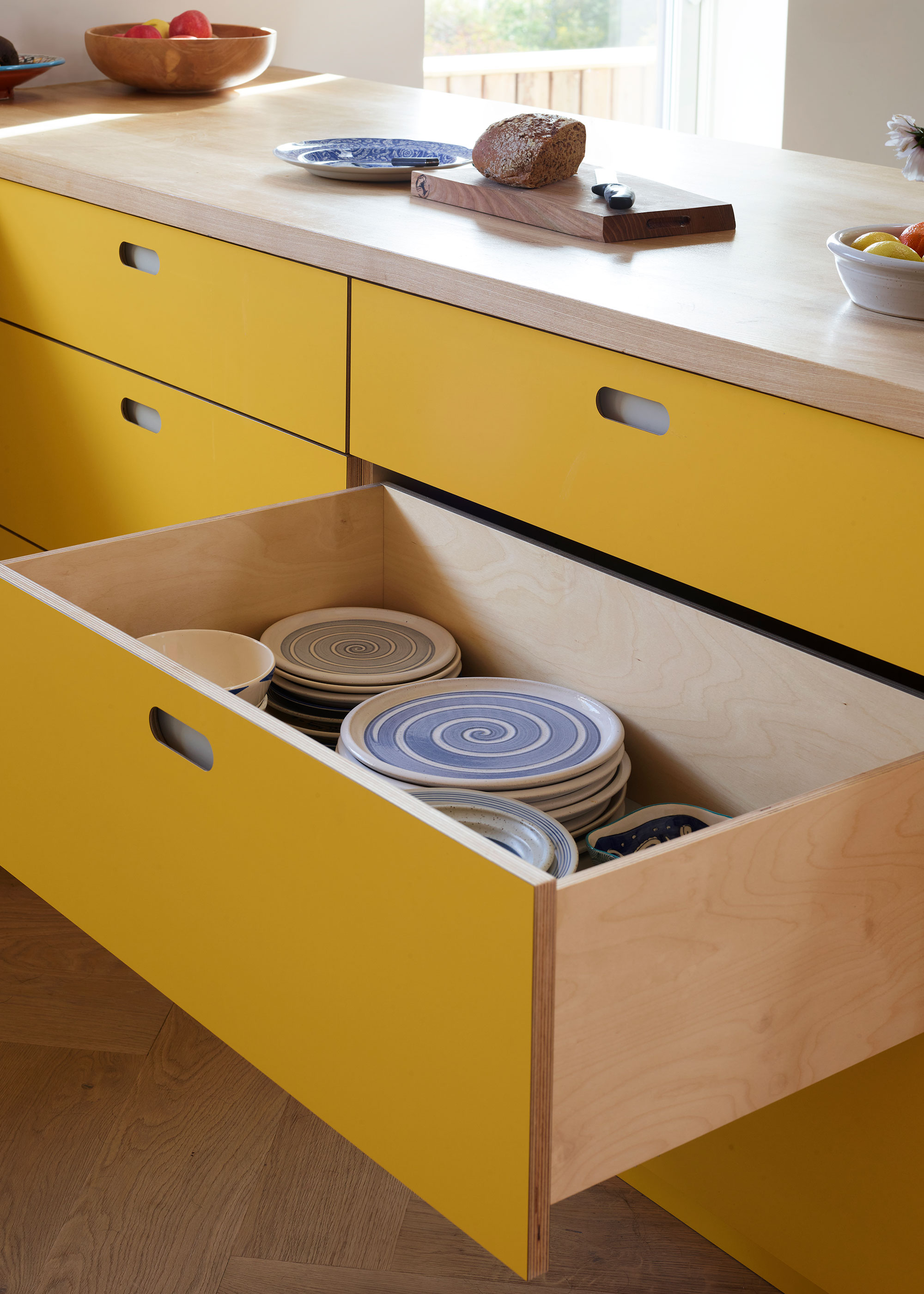 bright yellow kitchen drawers with plates inside