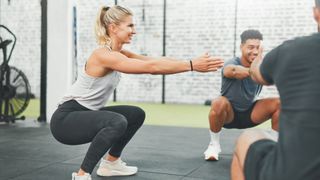 Woman squatting in a circle with other gym-goers