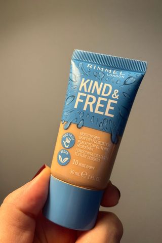 a hand holding a rimmel kind and free foundation