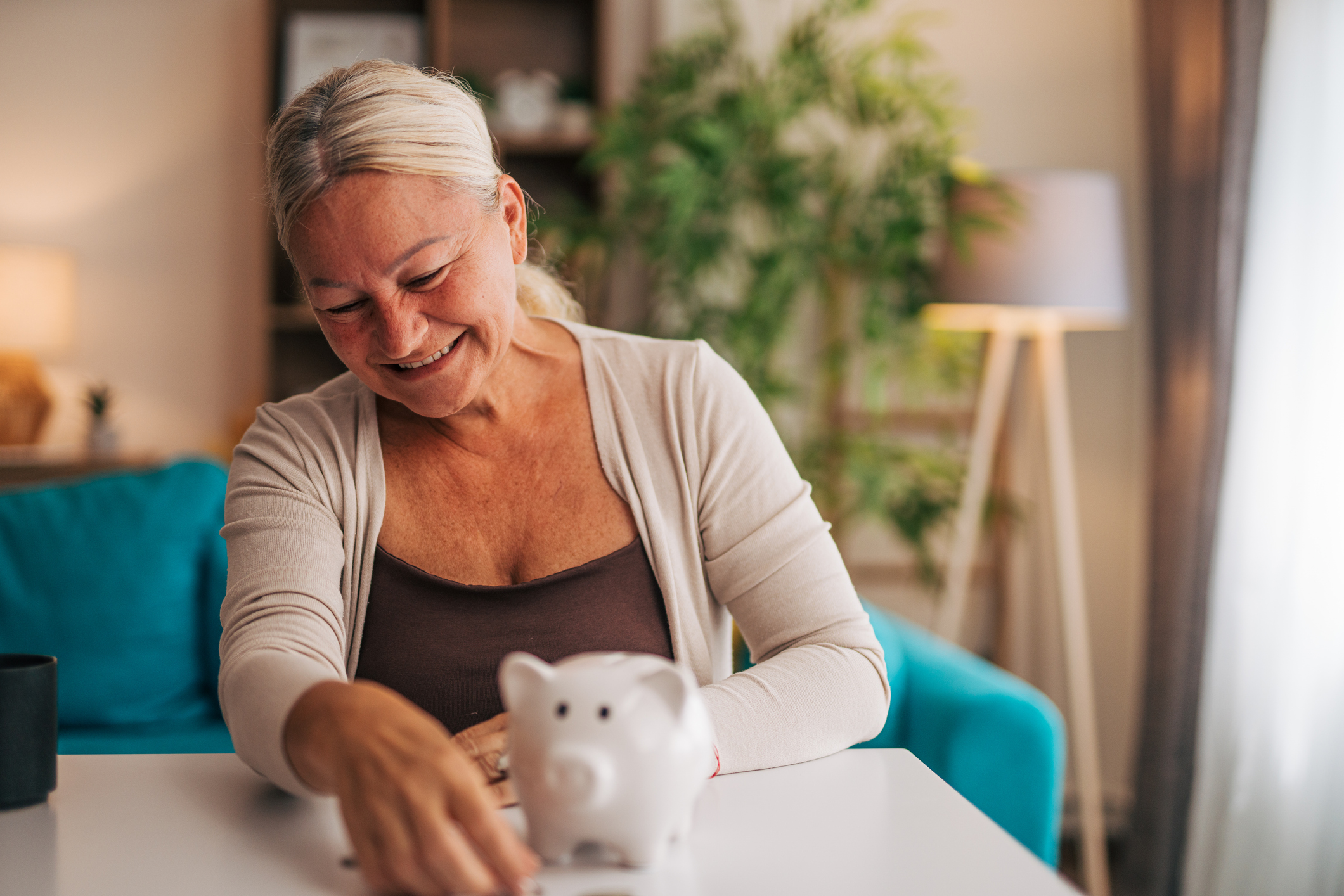 A woman smiling at a piggy bank