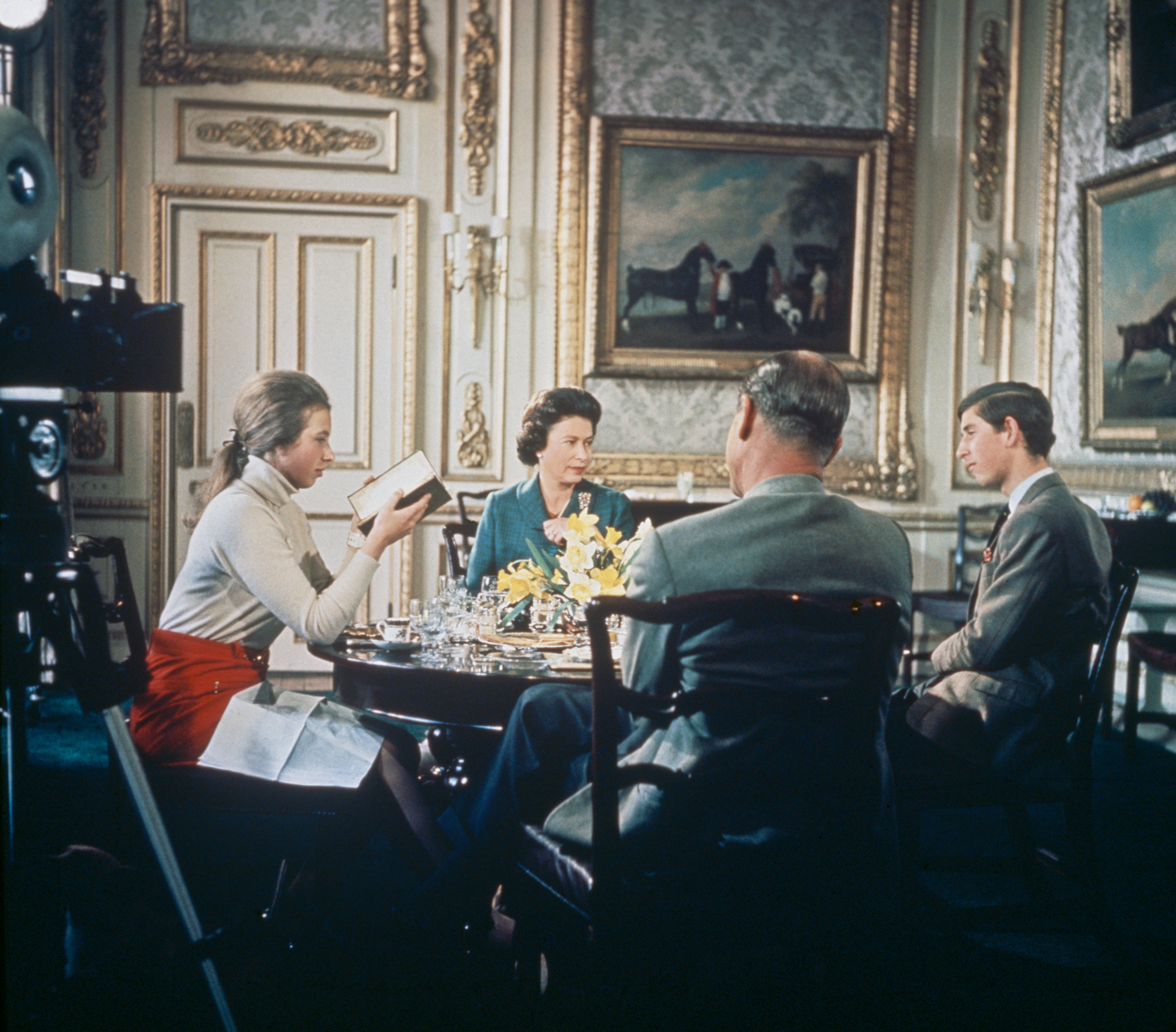 Queen Elizabeth, Prince Charles and Princess Anne sitting at a dining table in the 1960s
