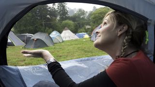 how to camp in the rain: woman feeling rain through tent
