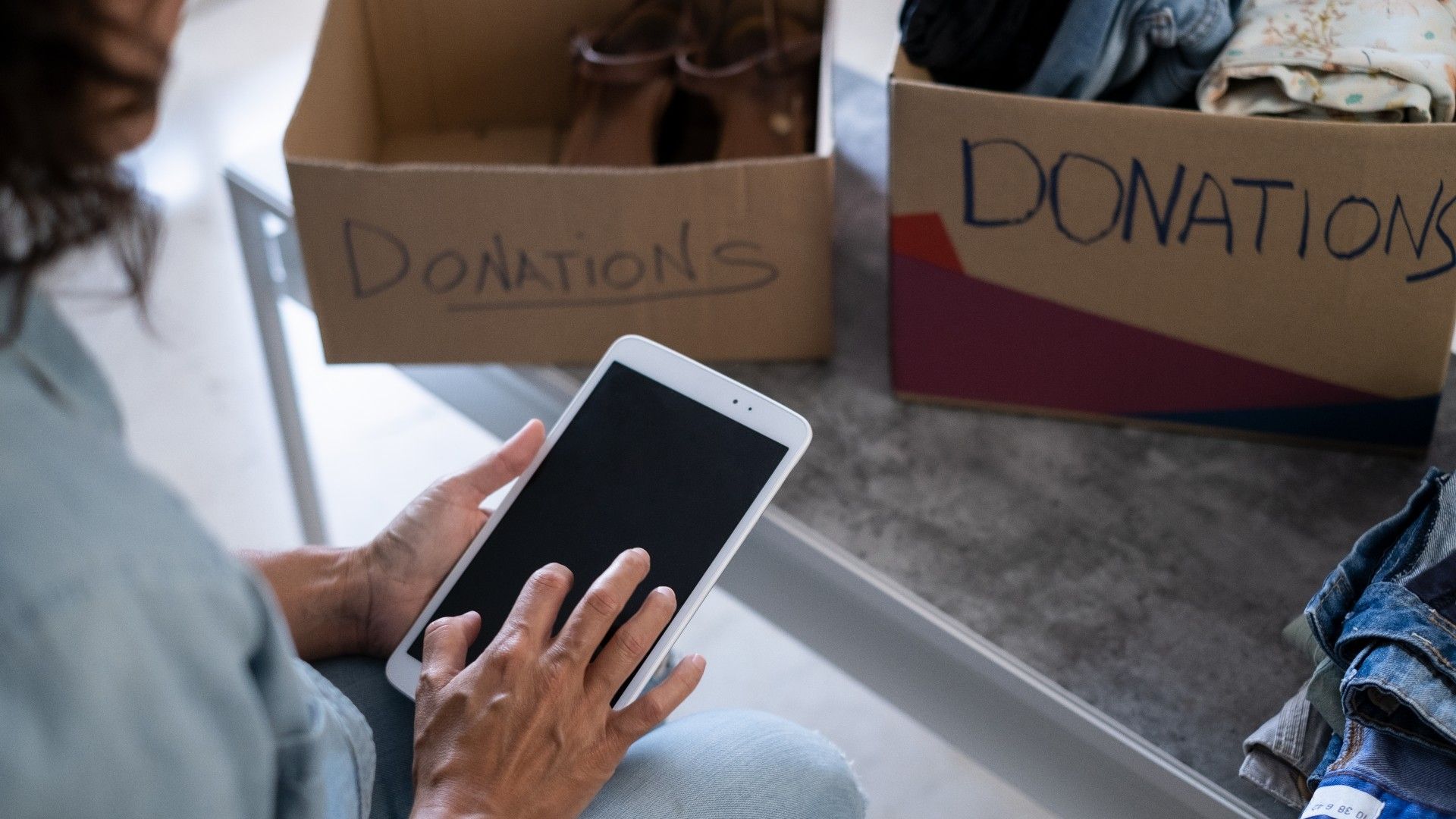 woman preparing donation boxes (on the counter) for donations using her tablet