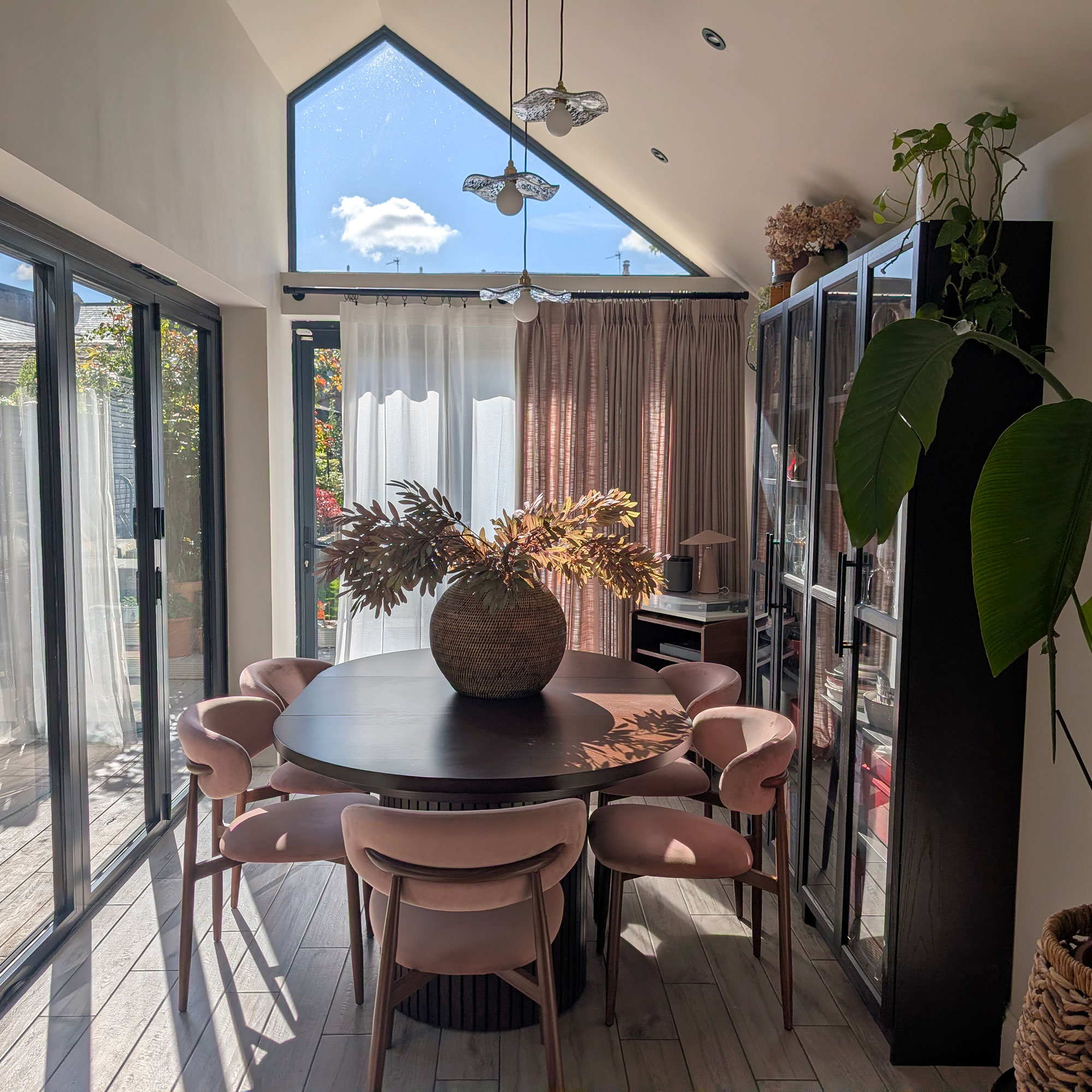 Dining area in extension with pitched roof, wooden table and pink chairs