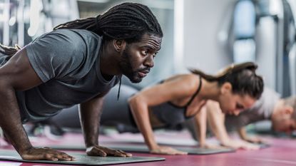 Man and woman doing push-ups in the gym during an AMRAP workout