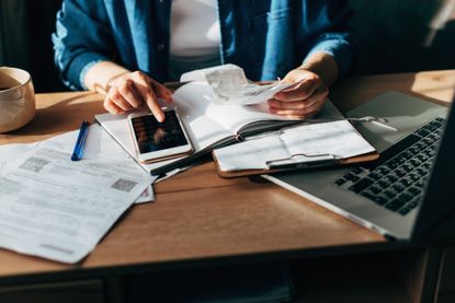 Woman using calculator and laptop for do taxes on wooden desk in office