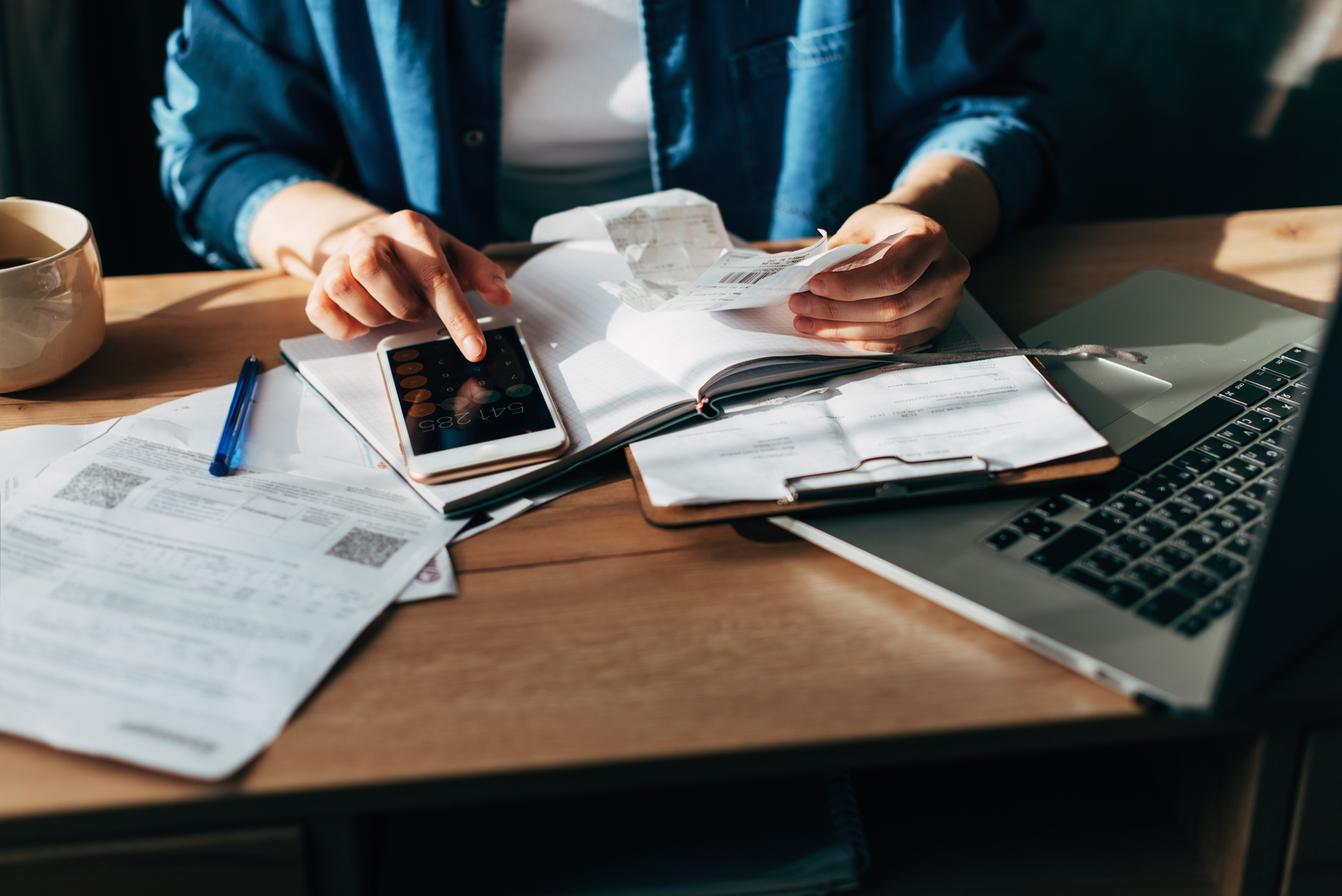 Woman using calculator and laptop for do taxes on wooden desk in office
