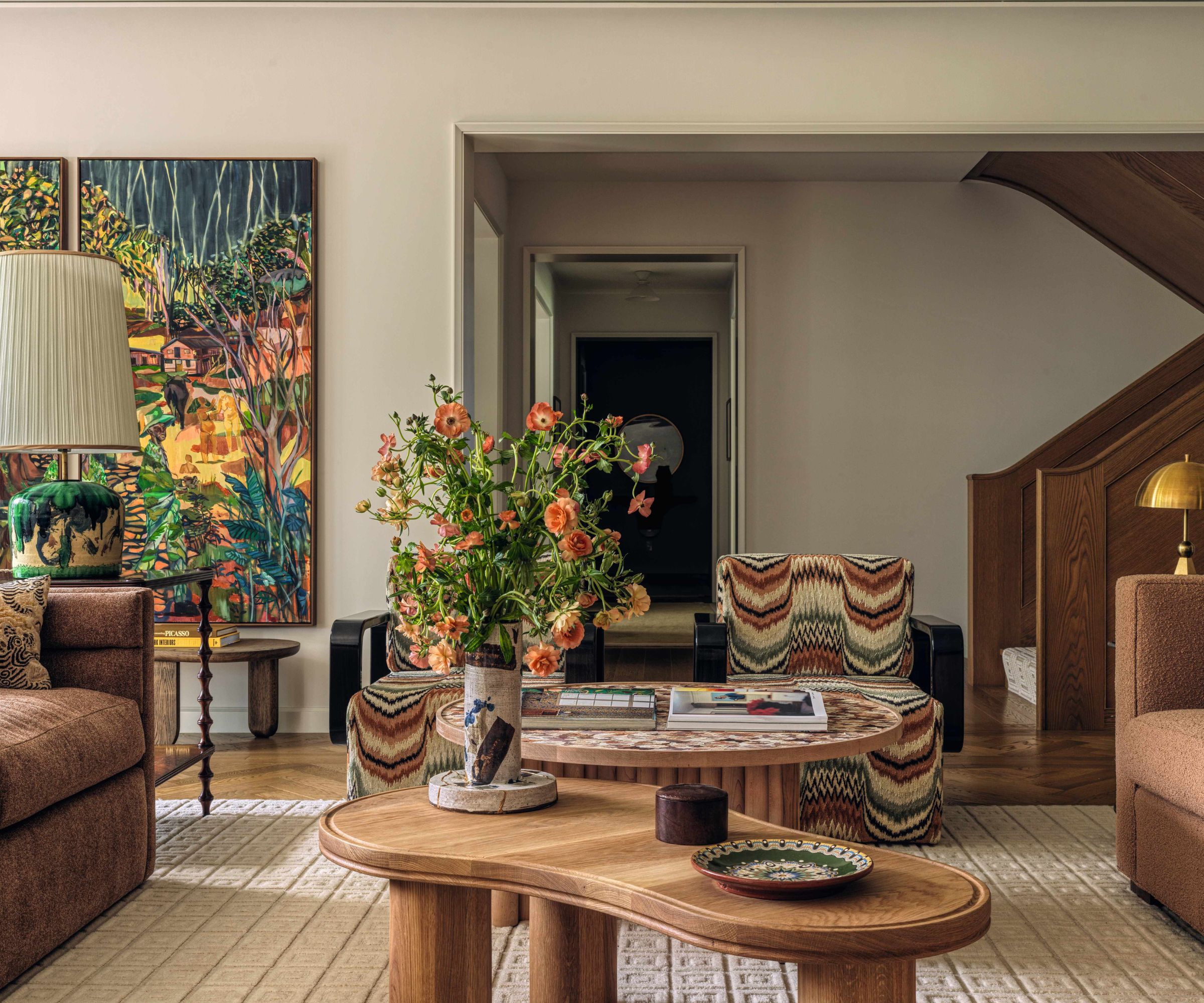 Modern living room with statement artwork curved wooden coffee table and brown sofas