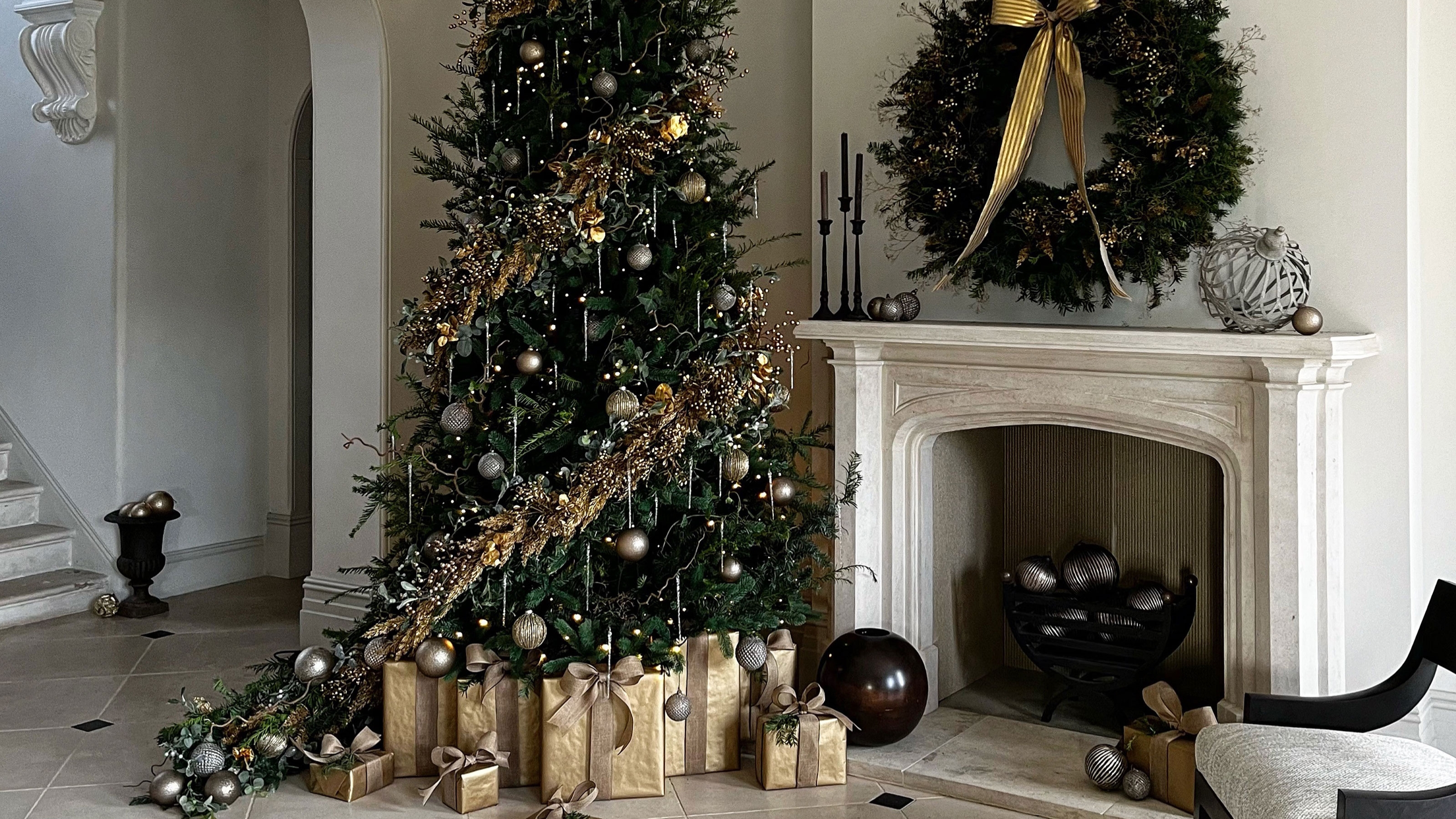 a christmas tree with gold decorations and a wreath over a fireplace