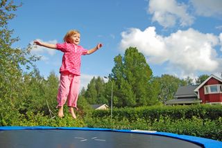 A girl bounces on a trampoline